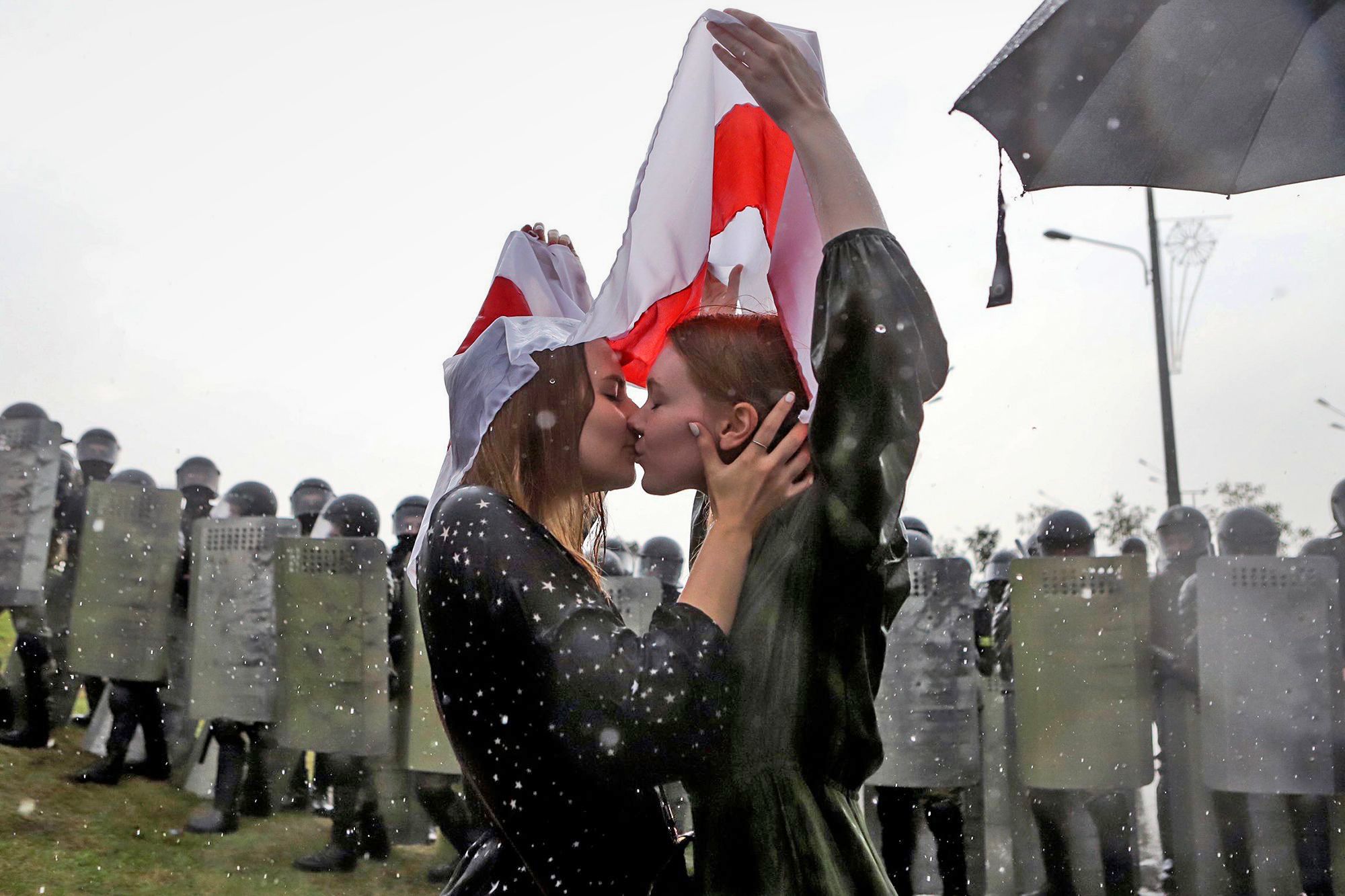 Two women kiss under the former red and white Belarusian flag used by the opposition as an emblem in Minsk, Belarus on Aug. 30.