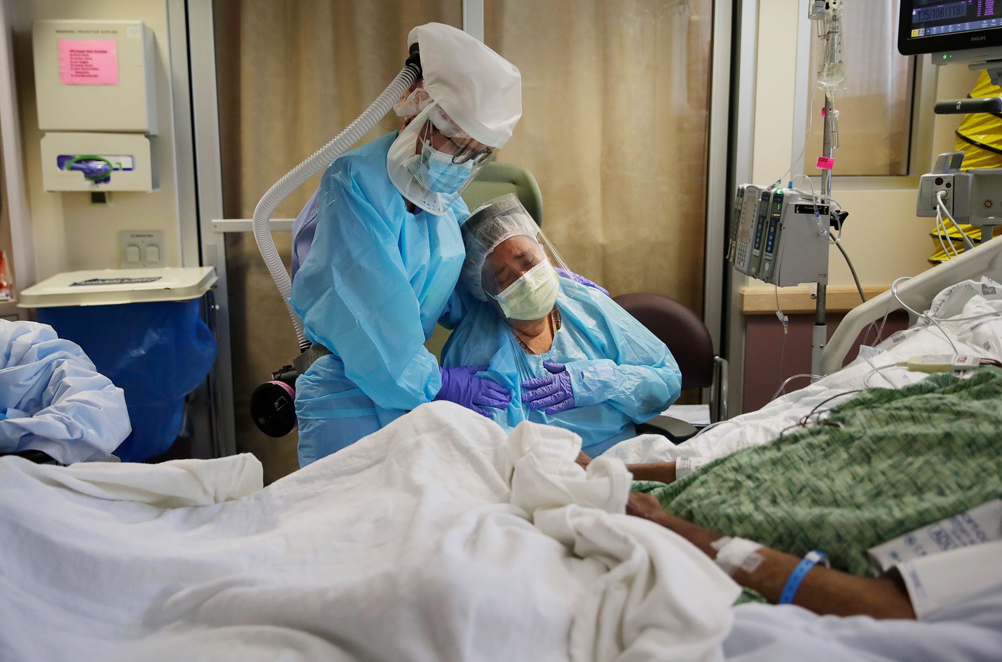 Nurse Michele Younkin comforts Romelia Navarro as she weeps while sitting at the bedside of her dying husband, Antonio, in St. Jude Medical Center's Covid-19 unit in Fullerton, Calif., on July 31. Antonio was the first Covid-19 patient to die on Younkin's watch.