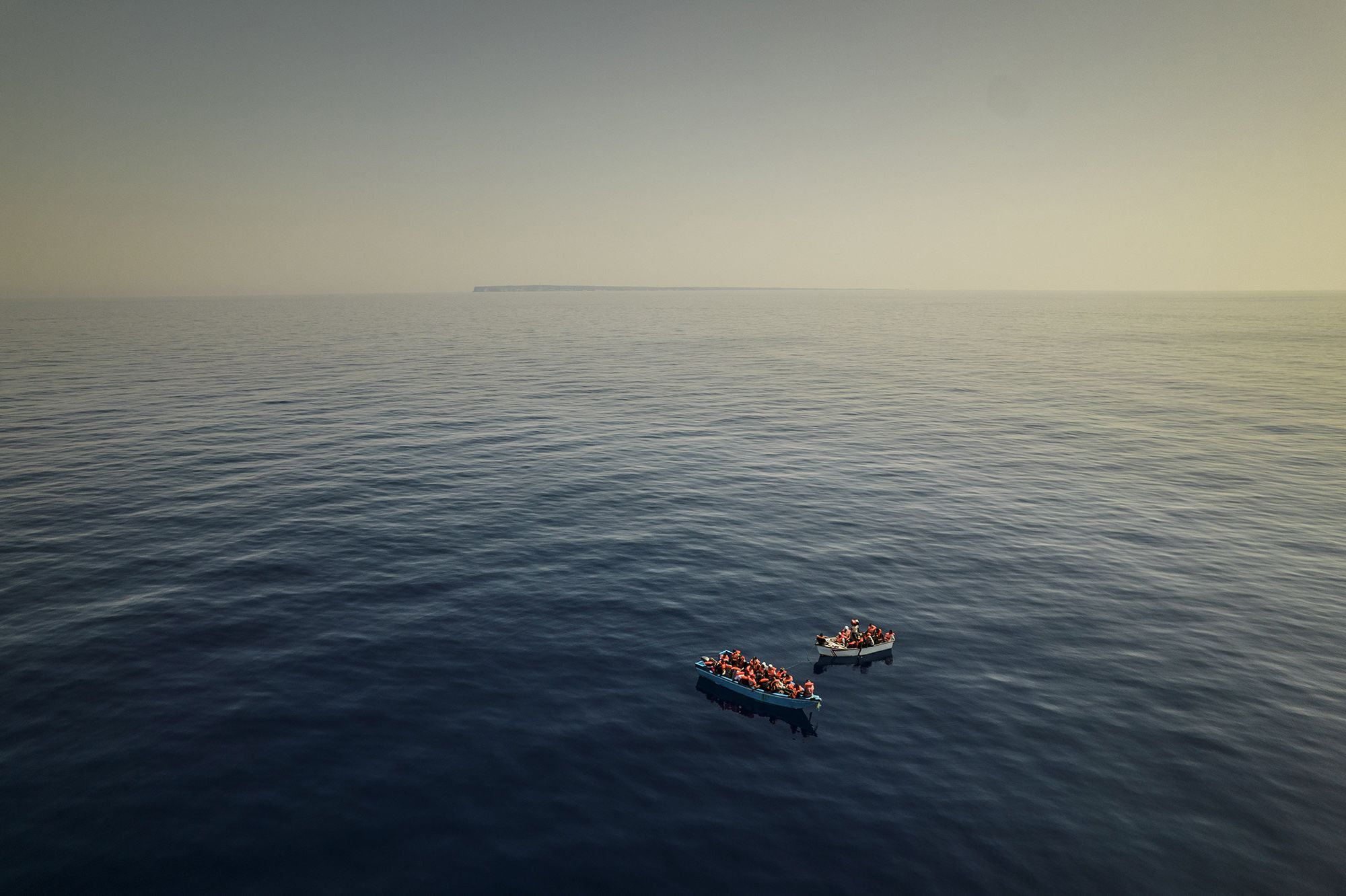 A group of migrants thought to be from Tunisia sit in precarious wooden boats as they wait to be assisted by a team from the Spanish NGO Open Arms, around 20 miles southwest of the Italian island of Lampedusa on July 29.