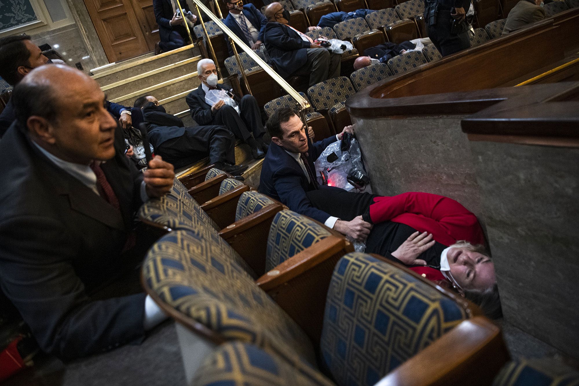 Rep. Jason Crow, D-Colo., comforts Rep. Susan Wild, D-Pa., while taking cover as protesters disrupt the joint session of Congress to certify the Electoral College vote on Jan. 6.