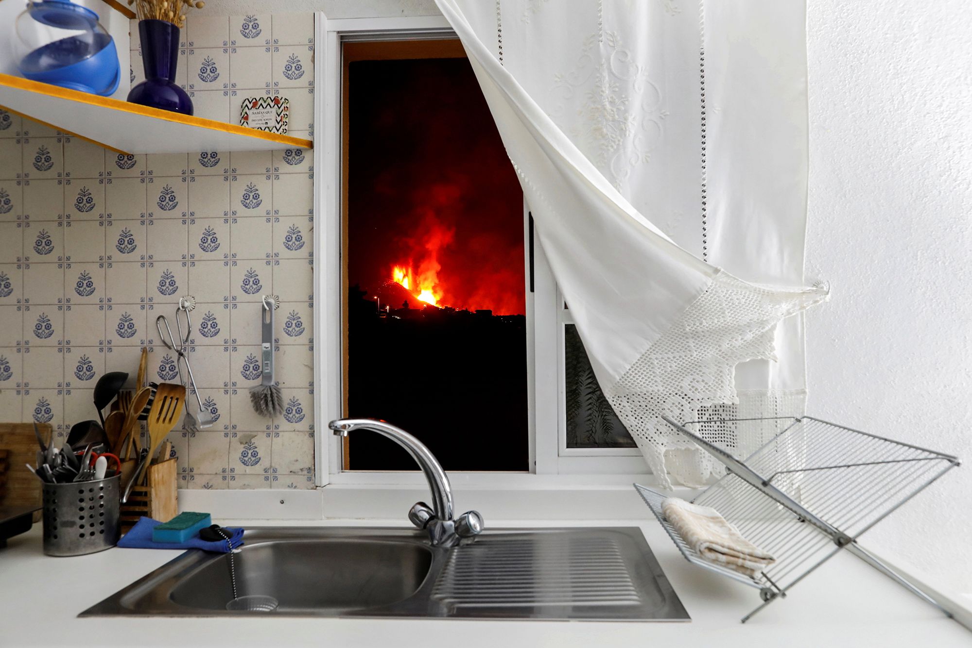 Lava from the eruption of a volcano glows outside the window of a kitchen on the Canary Island of La Palma, Spain, on Sept. 28.