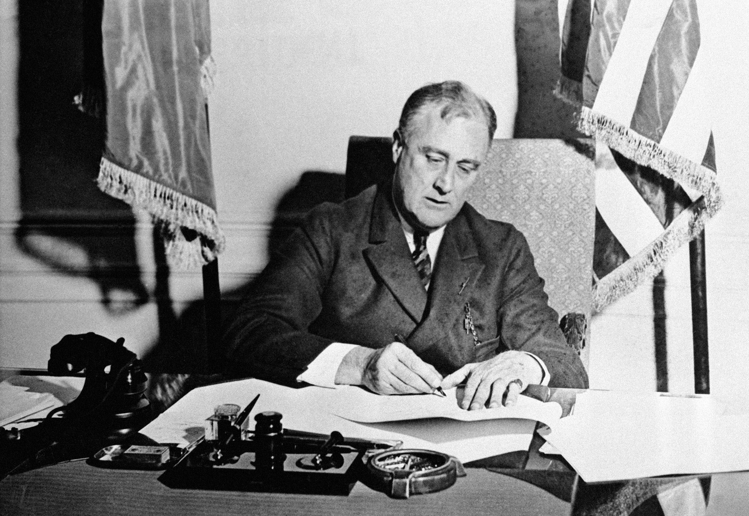 President Franklin Roosevelt signs New Deal emergency banking legislation on March 9, 1933.