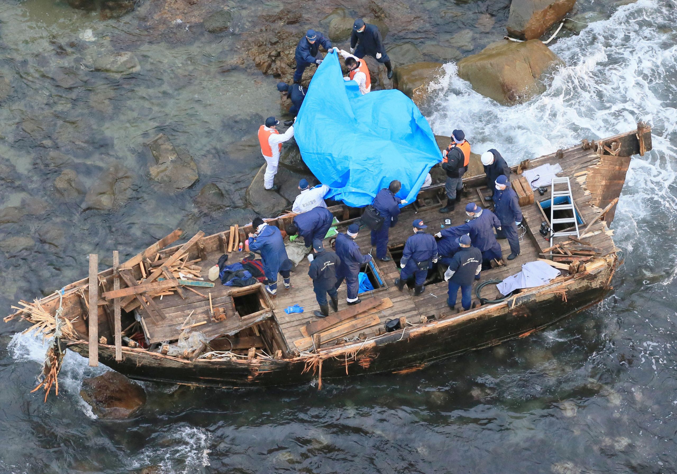 Police officers investigate a wooden boat marked with Hangul characters on Sado island, Japan, on Nov. 28, 2012.